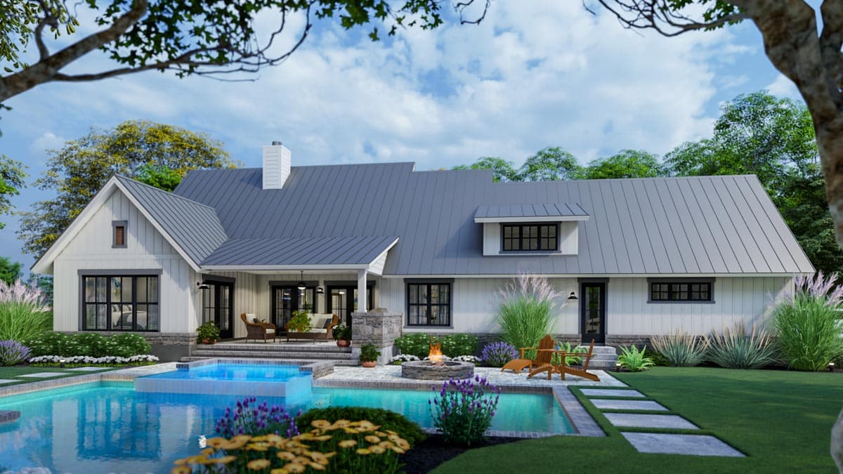 Exterior view of a modern farmhouse with a pool, fire pit, and outdoor seating. White siding and gray roof under a partially cloudy sky.