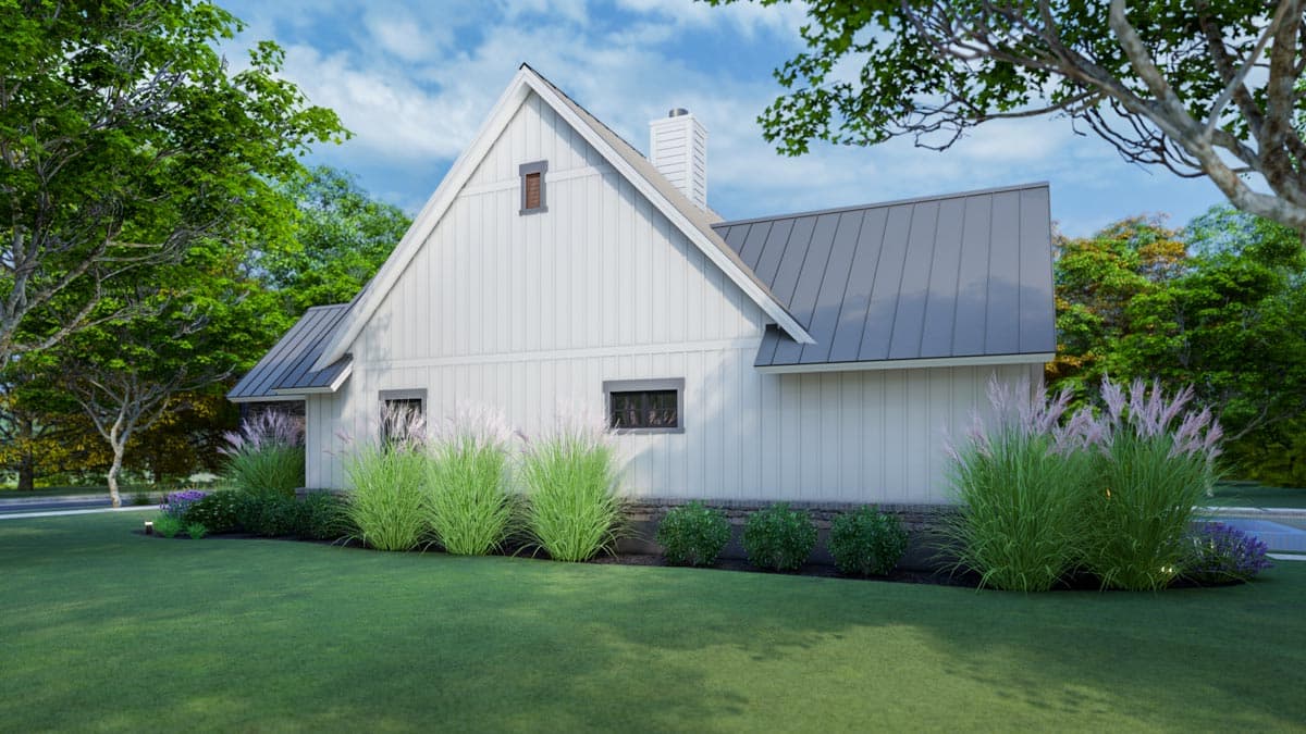 A modern, white-sided house with a dark gray roof sits surrounded by lush green lawn and landscaping. Tall ornamental grasses line the foundation.