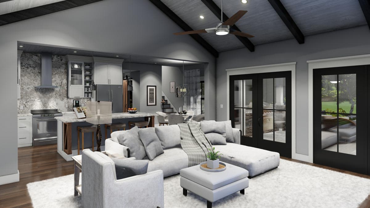 A modern, open-concept living space with a kitchen visible in the background. A large sectional sofa sits on a fluffy rug, with access to a patio.