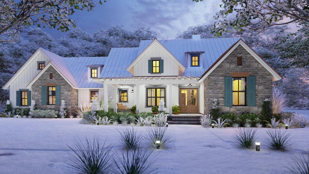 A snow-covered house at dusk. The white siding contrasts with the stone accents and dark window frames. Soft interior lights glow warmly.