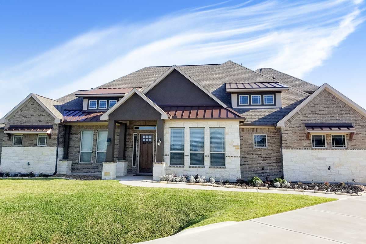 House plan exterior: One-and-a-half story, brick and stone, gabled entrance, metal roof dormers, and awnings.