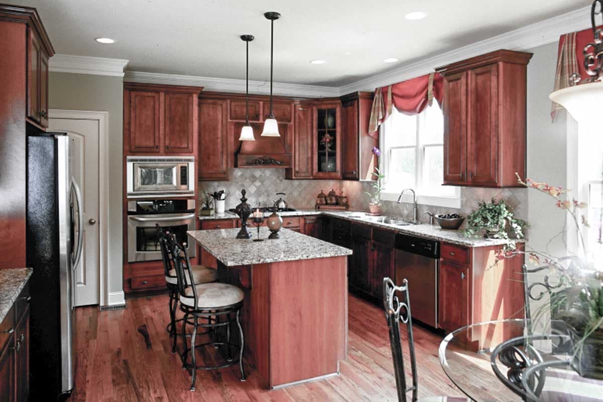 Kitchen with wood cabinets, granite-top island, stainless steel appliances, and pendant lighting.