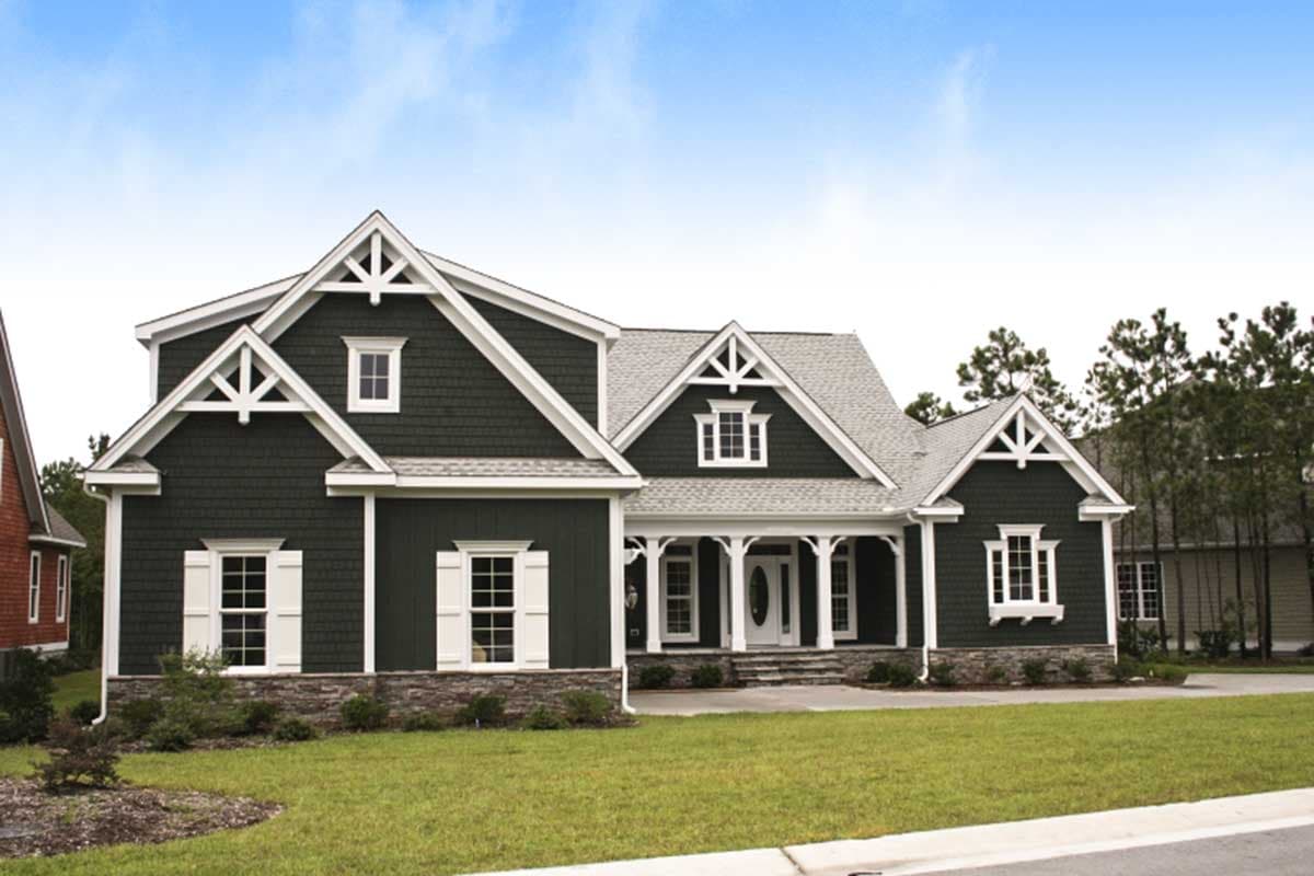 House plan exterior: Two-story home with dark green siding, stone accents, gabled dormers, and a covered front porch.