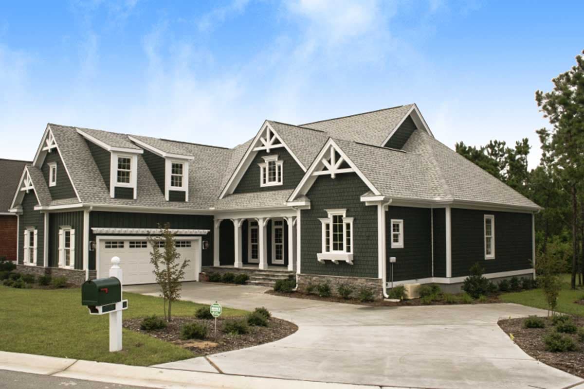 House plan exterior with a dark green shingle facade, gabled dormers, a front-facing garage, and a covered porch with columns.