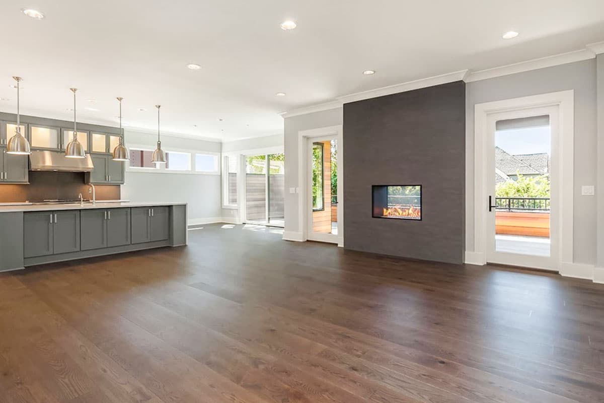 Open-concept living area with modern kitchen, fireplace, and sliding glass doors to an outdoor deck.