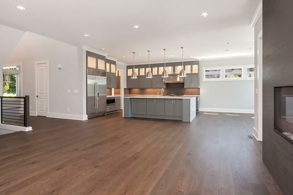 Open concept kitchen with gray cabinets, stainless steel appliances, island, and pendant lights.