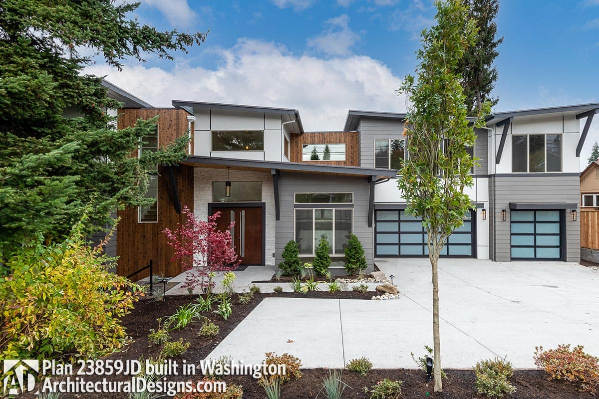 Modern house plan exterior with multiple gables, wood siding, stone facade, and three glass-paneled garage doors.