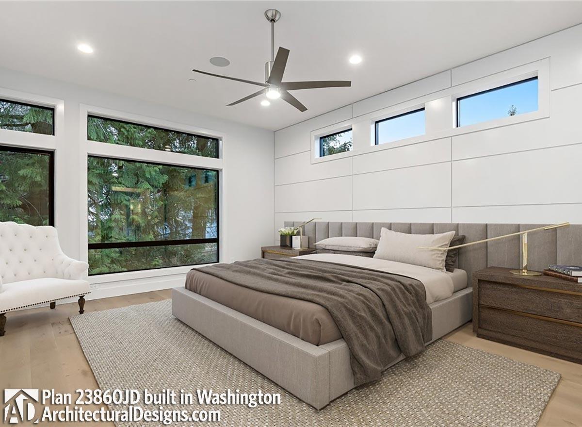 Primary bedroom with platform bed, large windows, and modern ceiling fan.