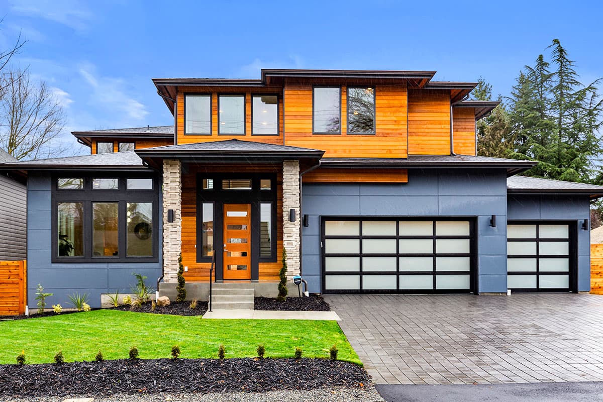 House plan exterior. Modern style, two-story home with wood siding, stone entry columns, and a two-car garage. Features flat rooflines.