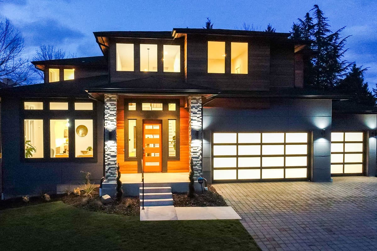 Modern two-story house plan exterior with a covered entry, multiple gables, and three glass garage doors.