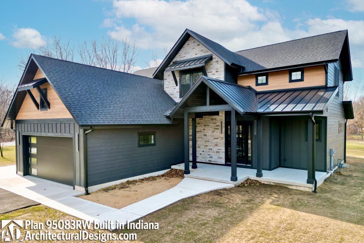 House plan exterior with dark horizontal siding, stone accents, and a covered entryway with dark support beams.