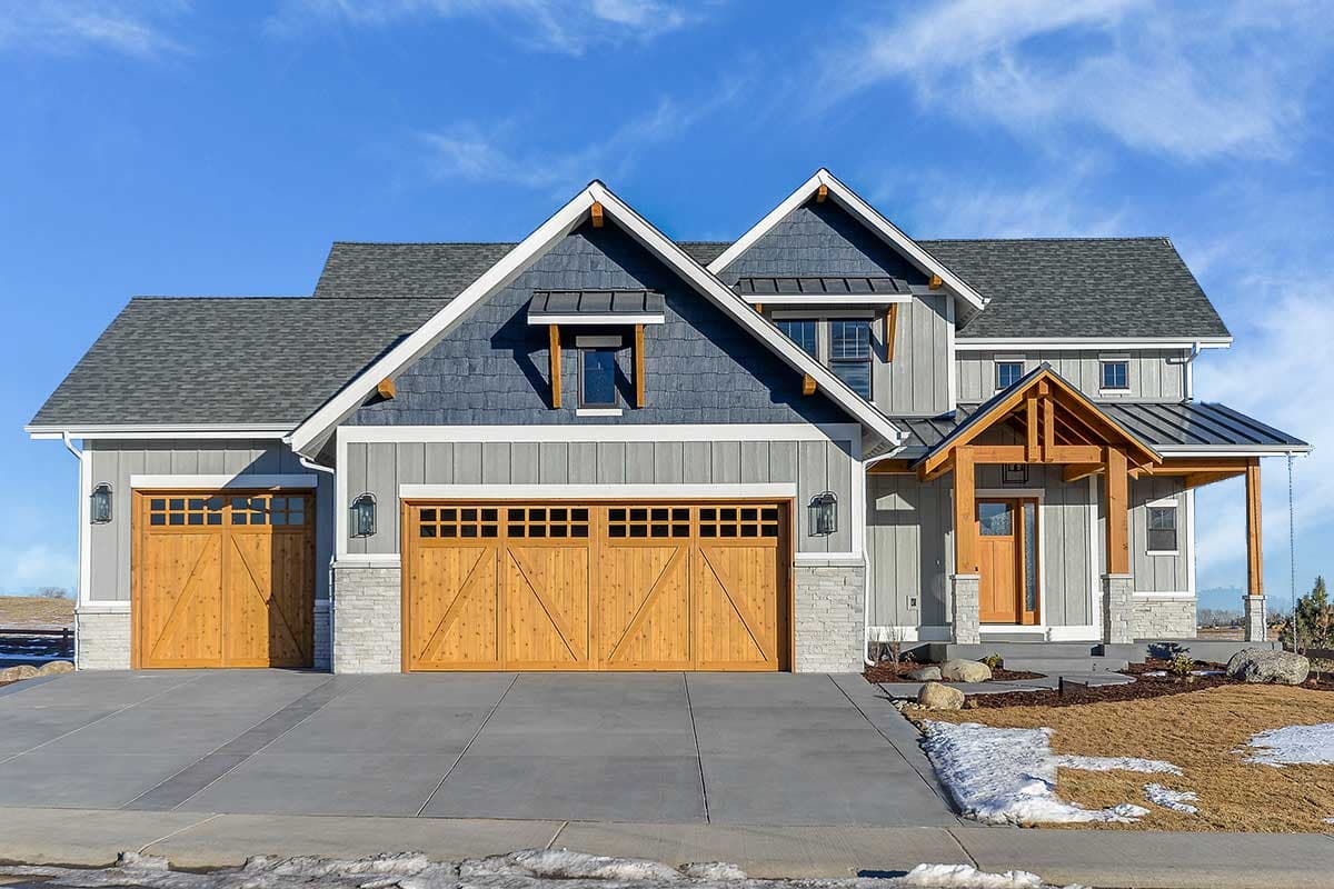 House plan exterior: Modern Farmhouse style, two stories, with gabled dormers, wood garage doors, and exposed rafter entry.