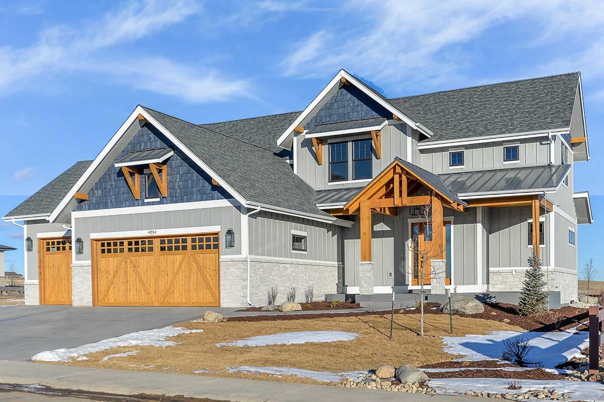 House plan exterior: Modern Farmhouse style, two stories, with dual wooden garage doors, stone accents, and a prominent wooden porch gable.