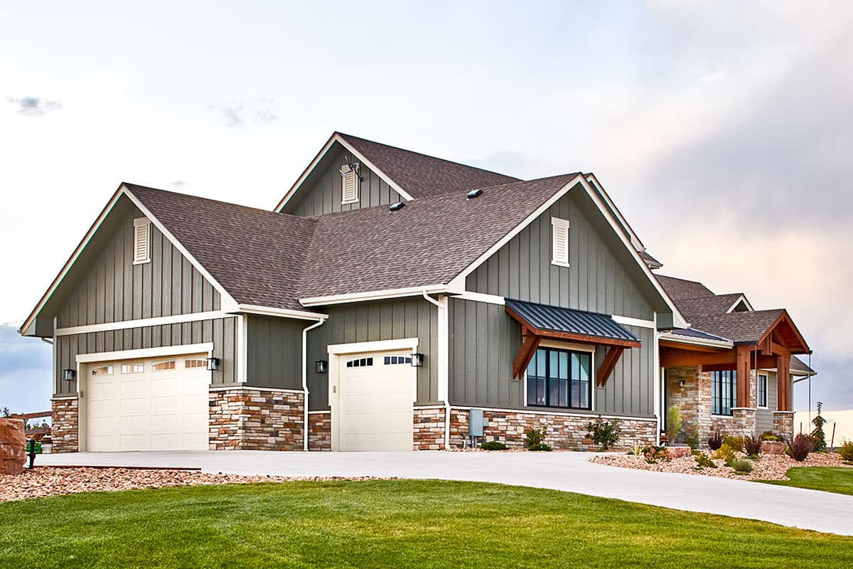 House plan exterior: Modern Farmhouse style, two-story with stone base, gabled rooflines, and a three-car garage.