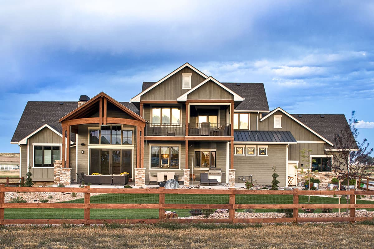 Modern Farmhouse house plan exterior with prominent gables, a covered patio with wood beams, and a second-story balcony.