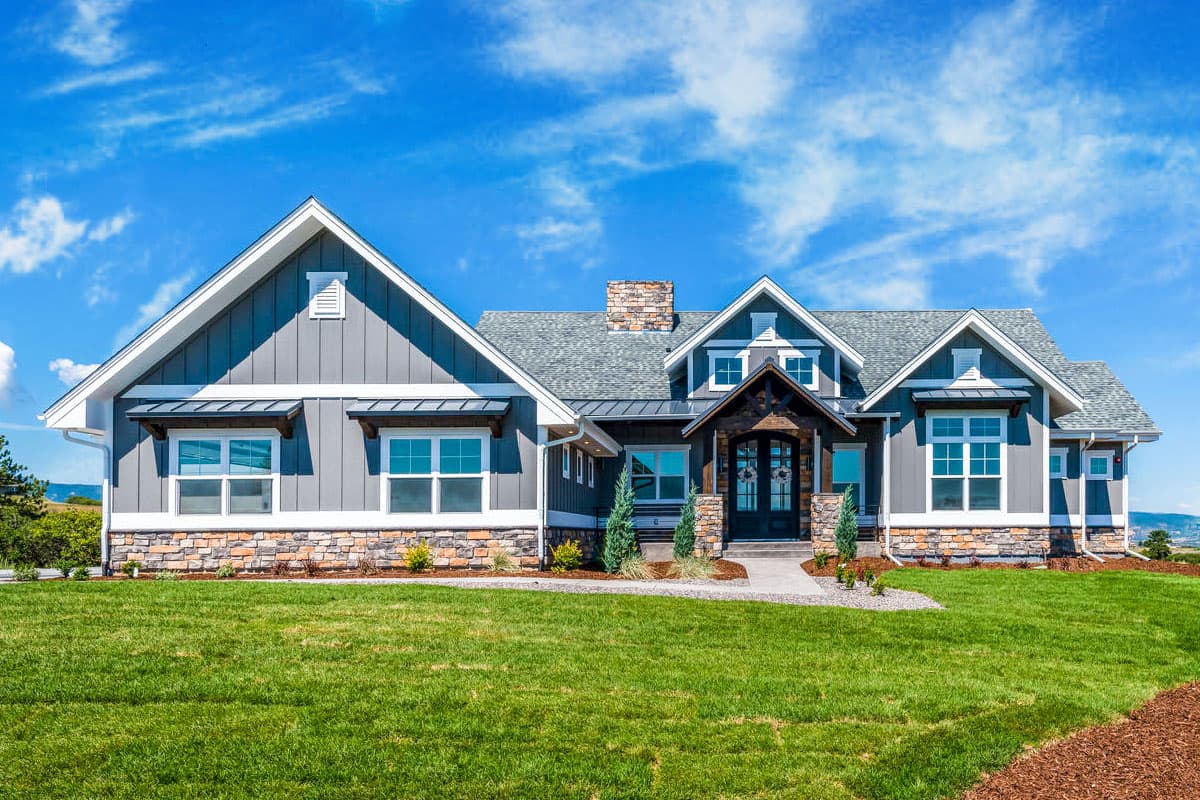 House plan exterior. Craftsman-style home with gables, stone accents, and covered entry. Features multiple window styles and a prominent chimney.