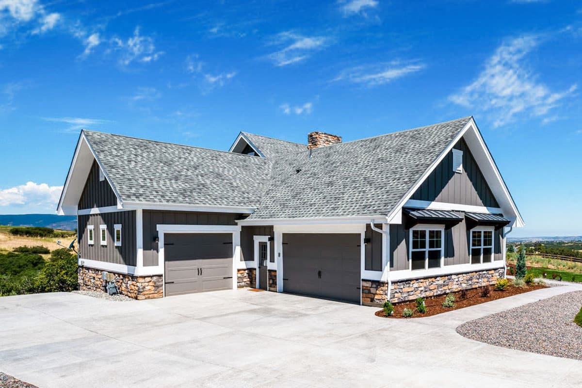 Modern Farmhouse house plan exterior with stone foundation, gray siding, gabled roof, and a three-car garage.