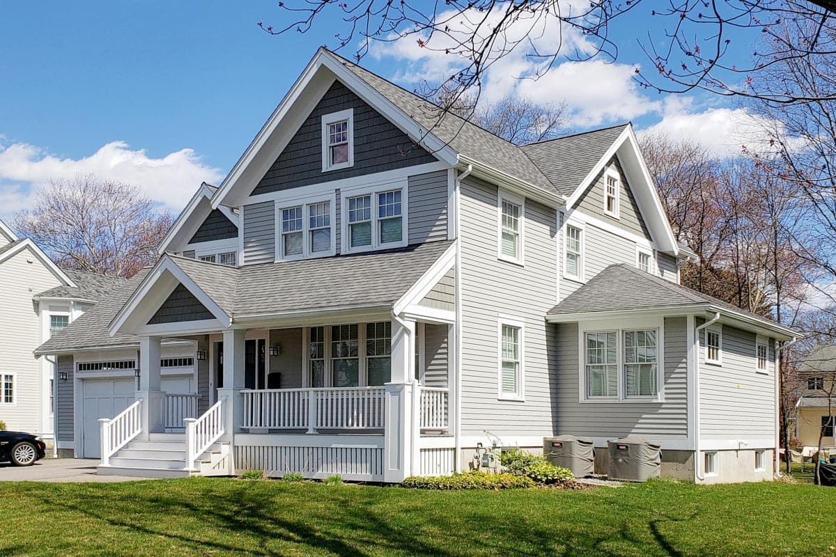 House plan exterior: Two-story home with covered front porch, gables, dormers, and attached garage.