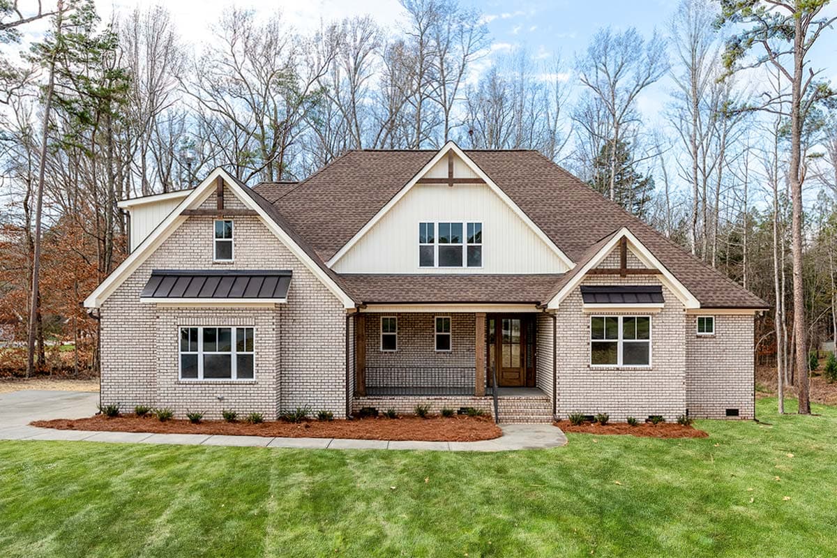 Modern Farmhouse house plan exterior with brick facade, gable dormers, and covered front porch with wood columns.