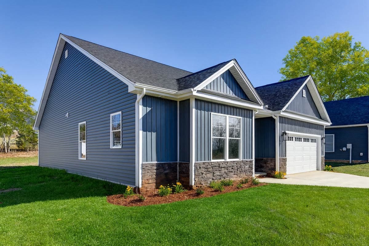 Ranch style house plan exterior with blue vinyl siding, stone accents, gable roof, and two-car garage.