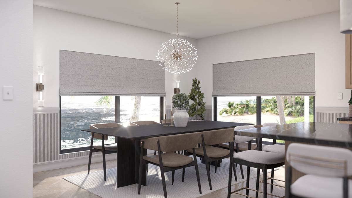 A modern dining room featuring a dark rectangular table and chairs, a large chandelier, and ocean views through the windows. 
