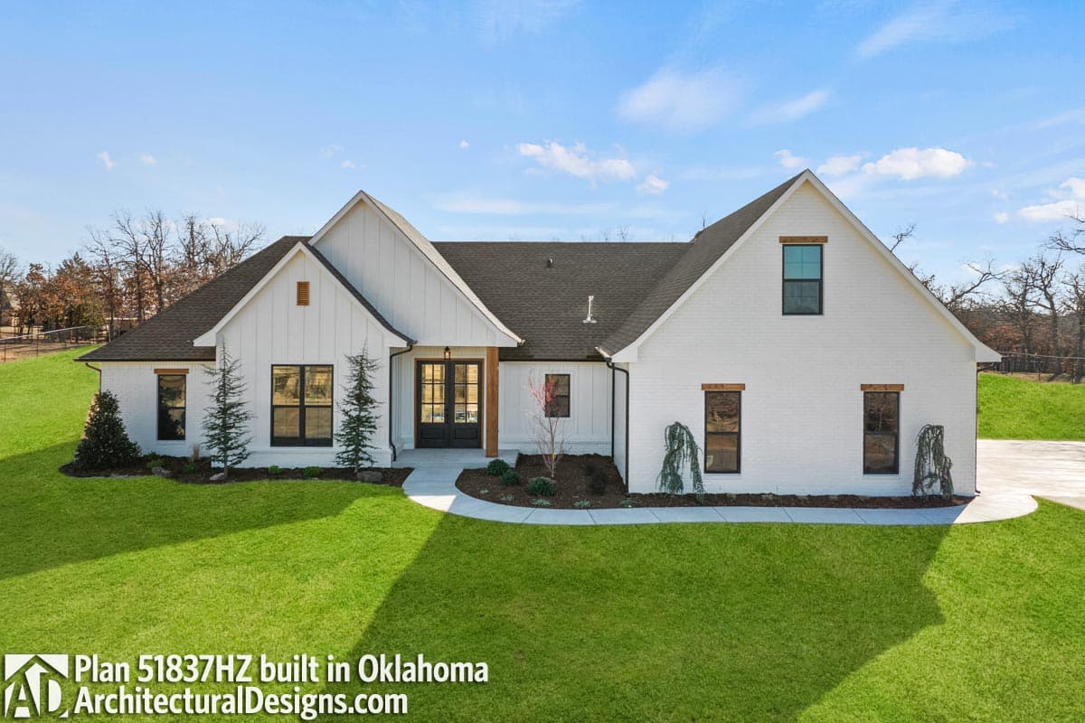 Modern Farmhouse plan exterior with white brick, board and batten siding, large gables, and double front doors.
