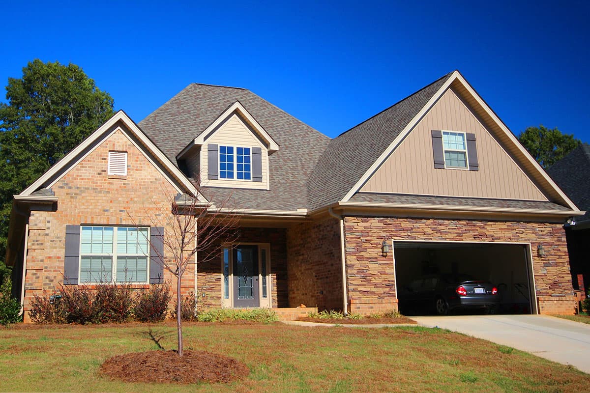 House plan exterior with brick and stone facade, two stories, gabled roof, dormers, and an attached garage.