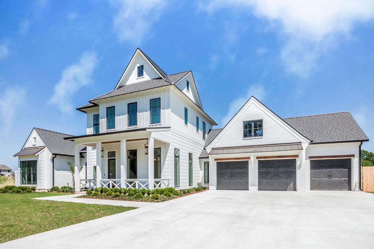 Modern Farmhouse style house plan exterior with white board and batten siding, prominent gables, covered front porch, and a three-car garage.