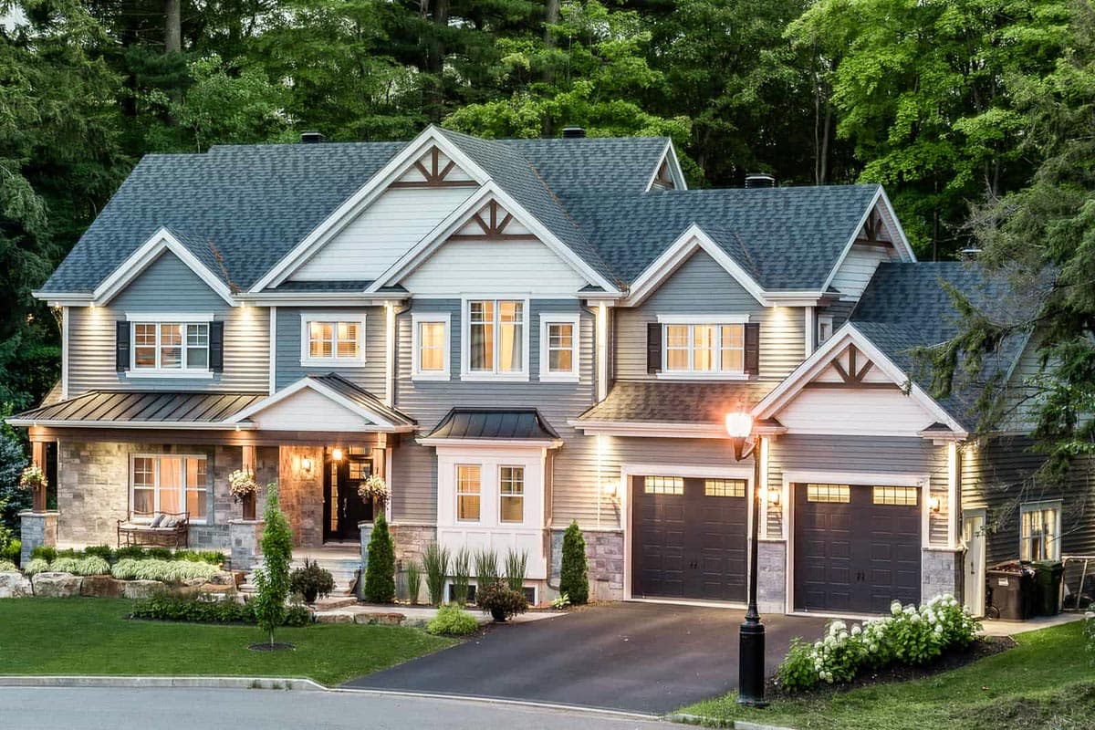 House plan exterior with Craftsman style. Two-story house with multiple gables, covered porch, and attached garage. Stone and clapboard siding.