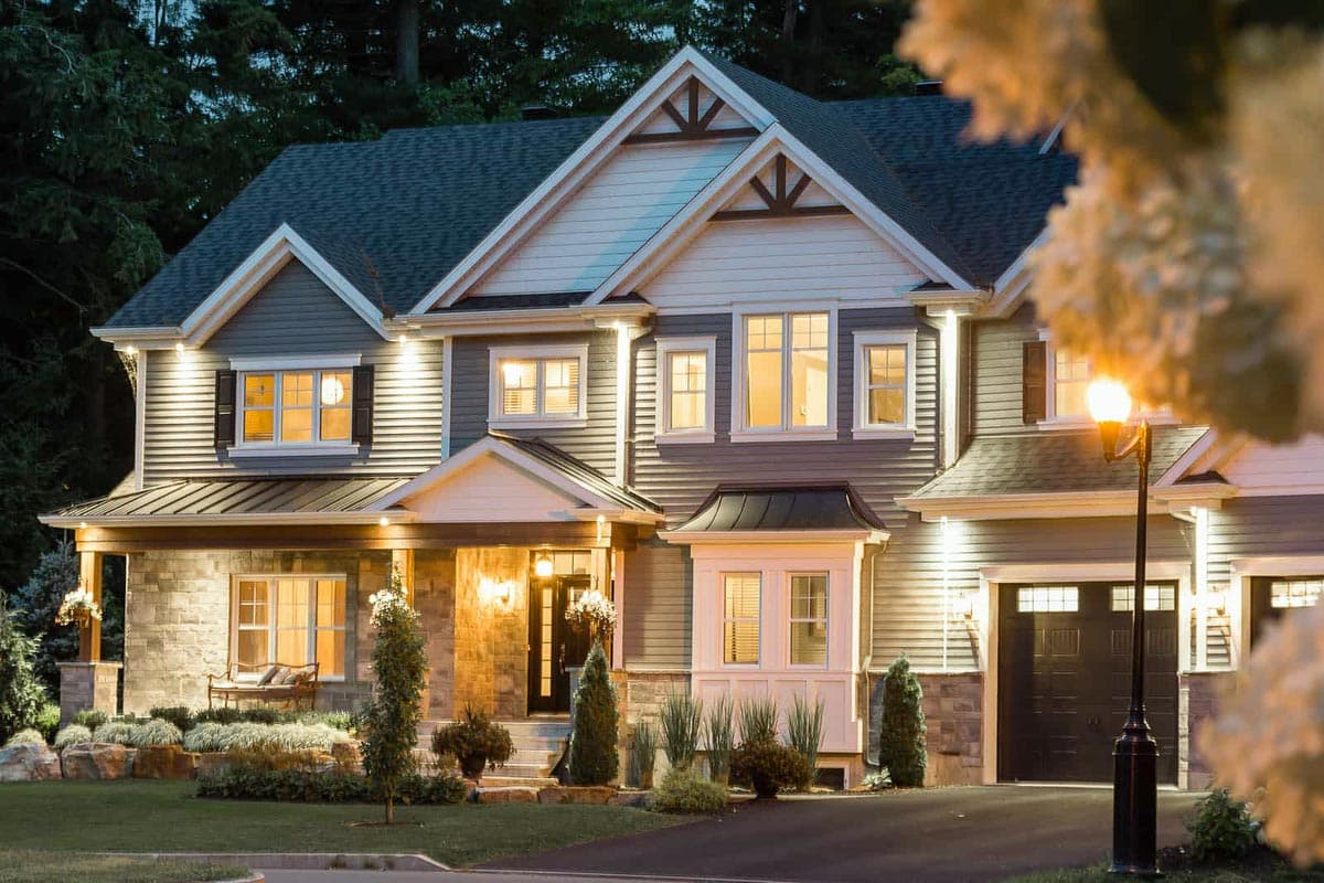 House plan exterior, two stories, with stone and siding, covered porch, multiple gables, and attached garage.