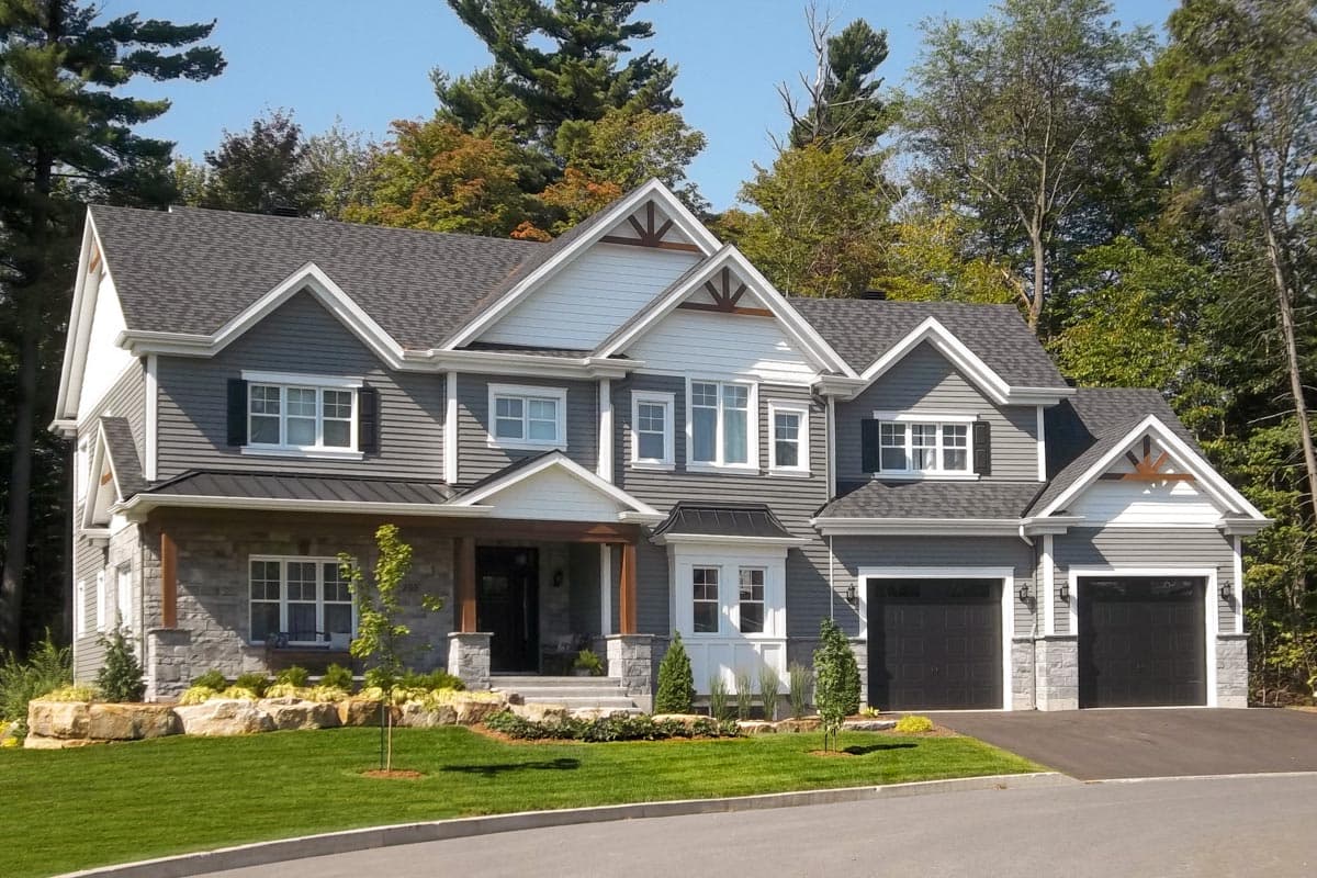 House plan exterior: Two-story Modern Farmhouse with gabled dormers, stone base, covered porch, and attached three-car garage.