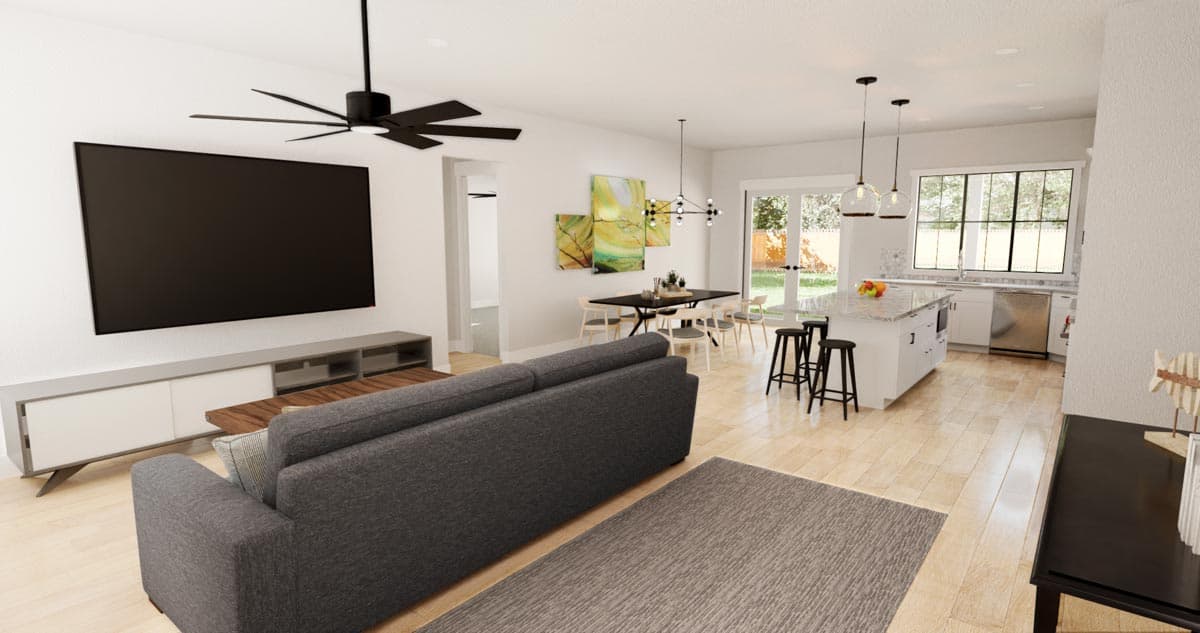 Open concept living area with kitchen island, dining table, and sofa facing a wall-mounted TV.