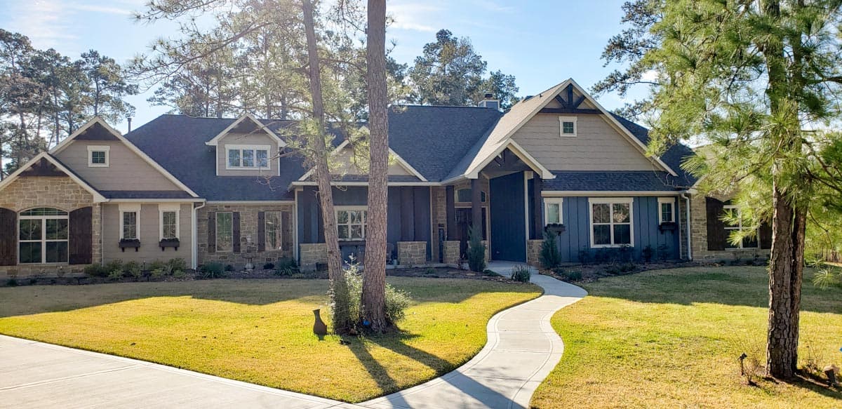 House plan exterior: Craftsman style, single-story with stone and siding, prominent gables, dormers, and covered entry.