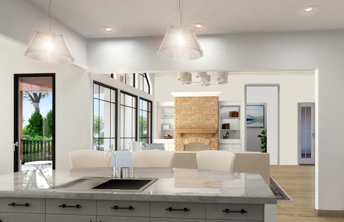 Kitchen island with sink overlooking great room with brick fireplace, large windows, and doorway to outdoor space.