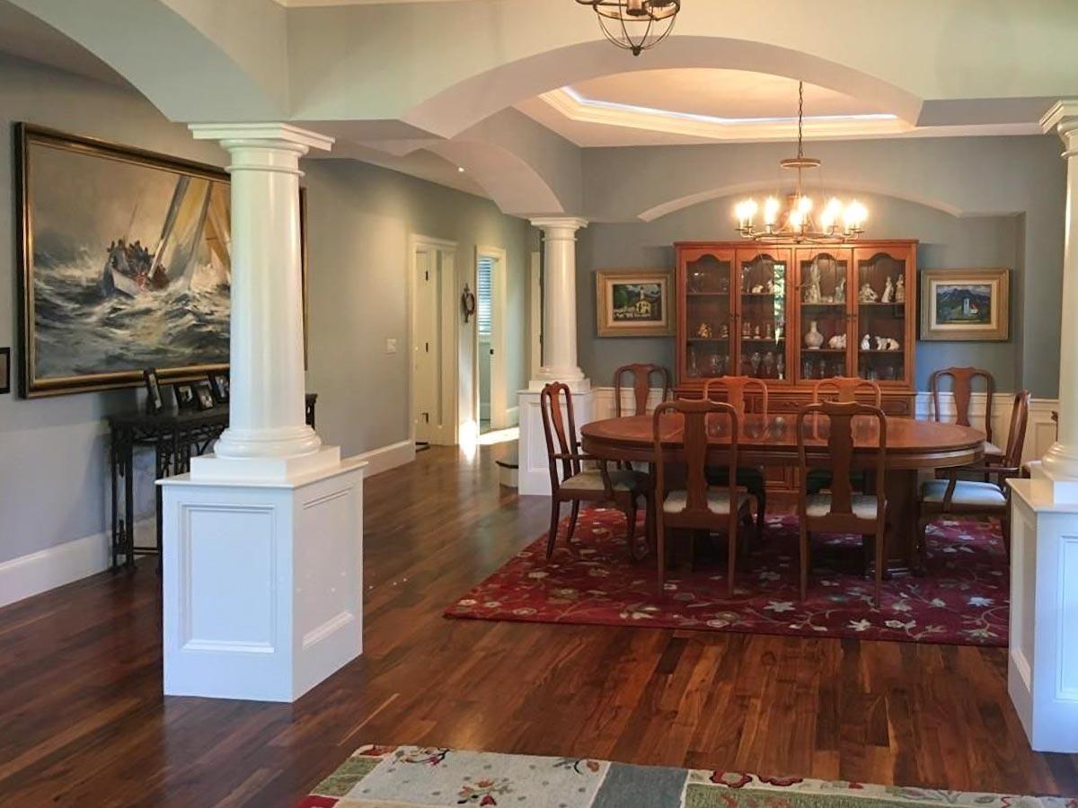 Interior view of dining room with oval table, china cabinet, and decorative columns.