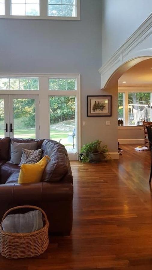 Interior view of a great room with a vaulted ceiling, large windows, and a brown leather sofa.