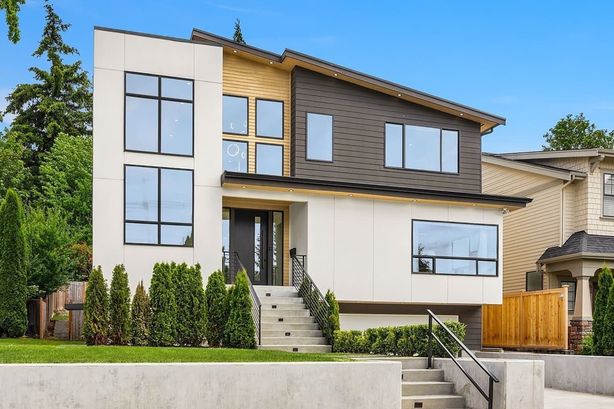 Modern house plan exterior with a two-story facade, asymmetrical rooflines, and a mix of white panels, wood siding, and dark cladding.