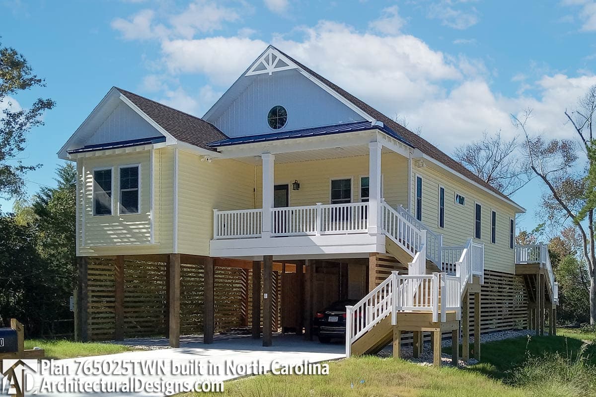 House plan exterior: Two-story elevated coastal style with wide porch, gabled dormer, and multiple staircases.