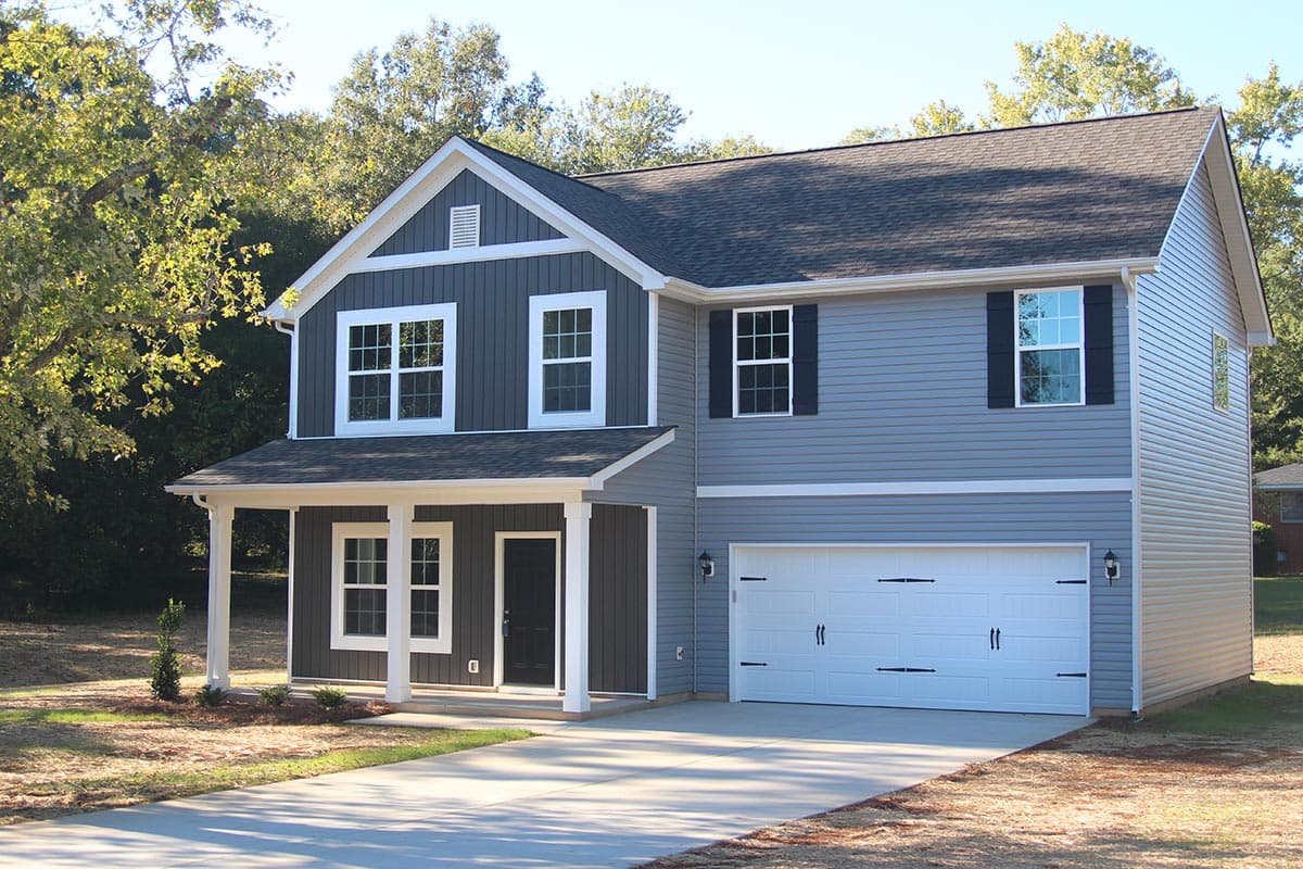 House plan exterior. Two-story, craftsman-style home with front porch, gables, and attached garage. Windows have black shutters.