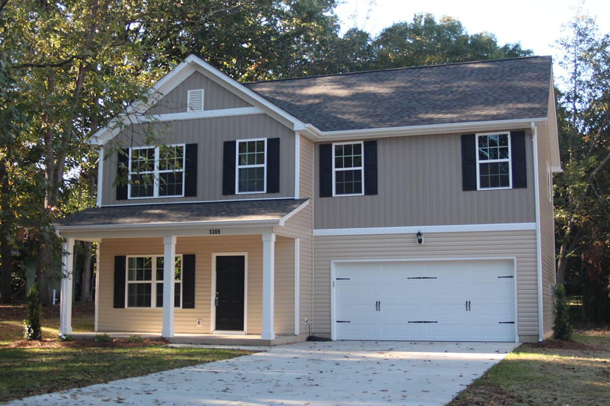 Two-story house plan exterior with a covered front porch, gable dormer, and attached two-car garage.