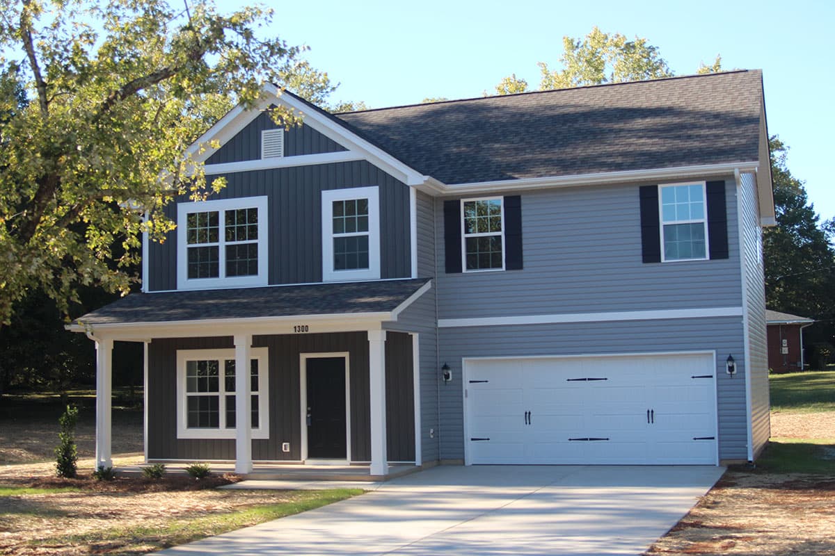 Two-story house plan exterior with covered porch, white columns, gable dormer, and two-car garage.
