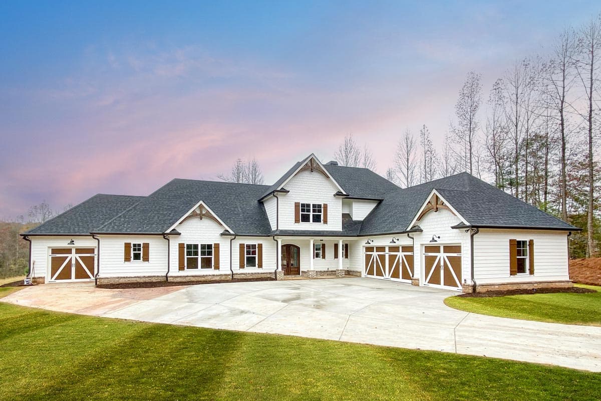 House plan exterior. Two-story Modern Farmhouse with gabled rooflines, multiple garage bays, and wooden shutters.