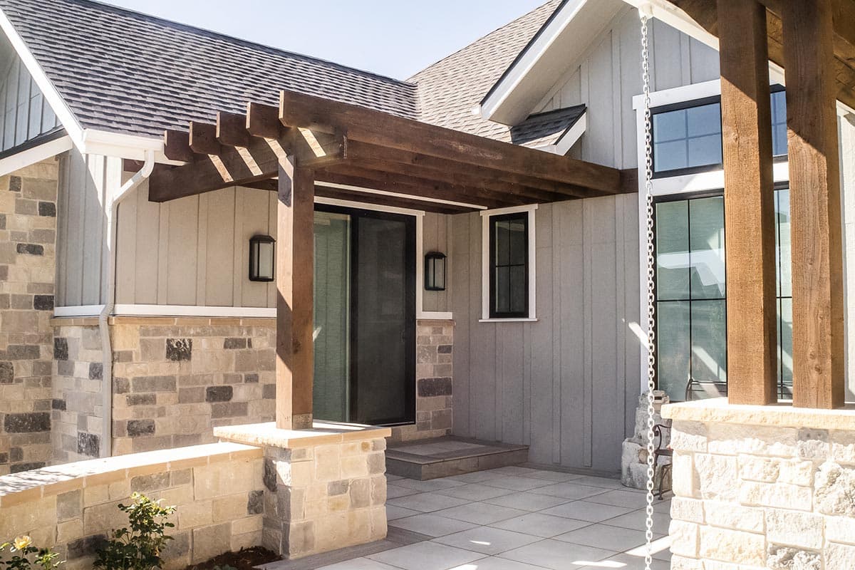 Modern Farmhouse house plan exterior with stone and board-and-batten siding, wooden pergola, and large windows.