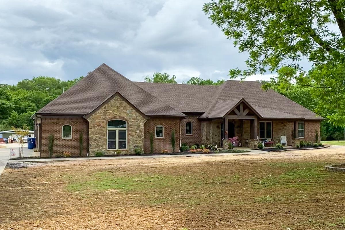 House plan exterior with brick and stone facade. Features include a front porch, gables, and a prominent roofline.