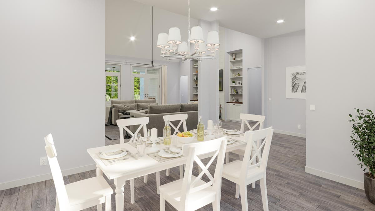 Dining area with white table and chairs, open to living room with sectional sofa and vaulted ceiling.