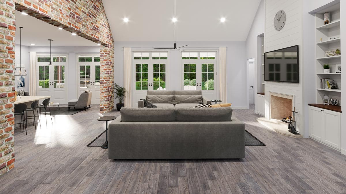 Great room interior with vaulted ceiling, brick accent wall, fireplace, and large French doors.