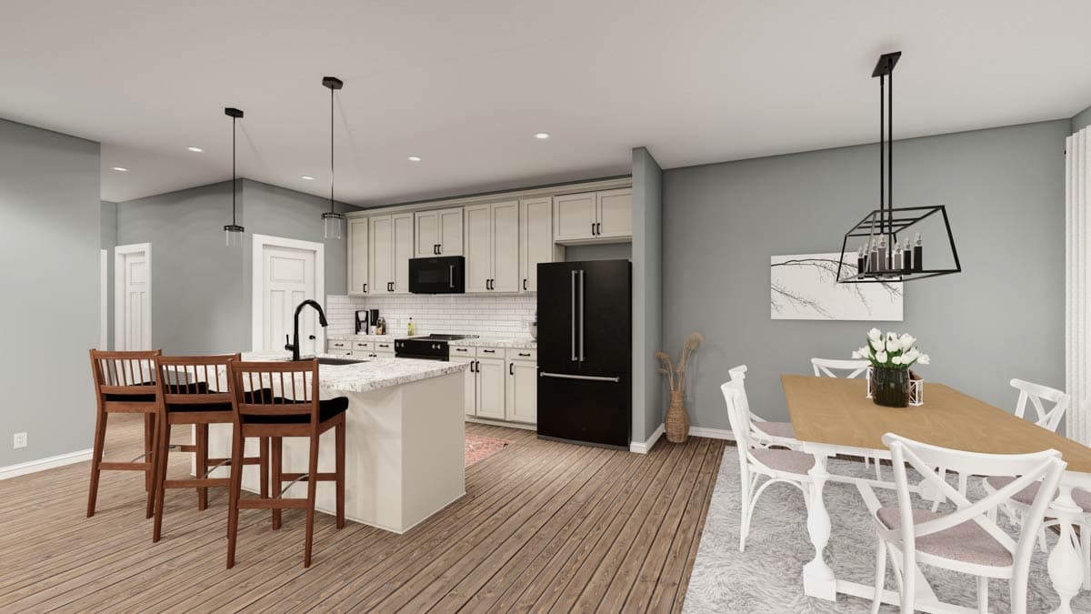 Interior view of kitchen and dining area with island, white cabinets, black appliances, and dining table.