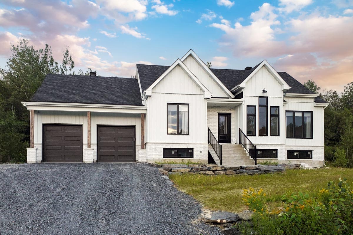 Modern house plan exterior with a white board and batten facade, gable rooflines, a two-car garage, and a raised entryway.