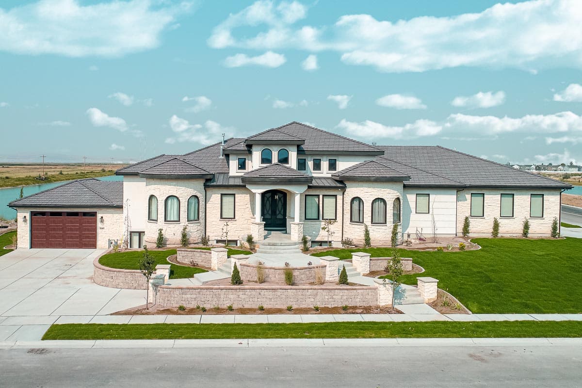 House plan exterior. Two-story, stucco facade with arched windows, multiple rooflines, and a three-car garage.
