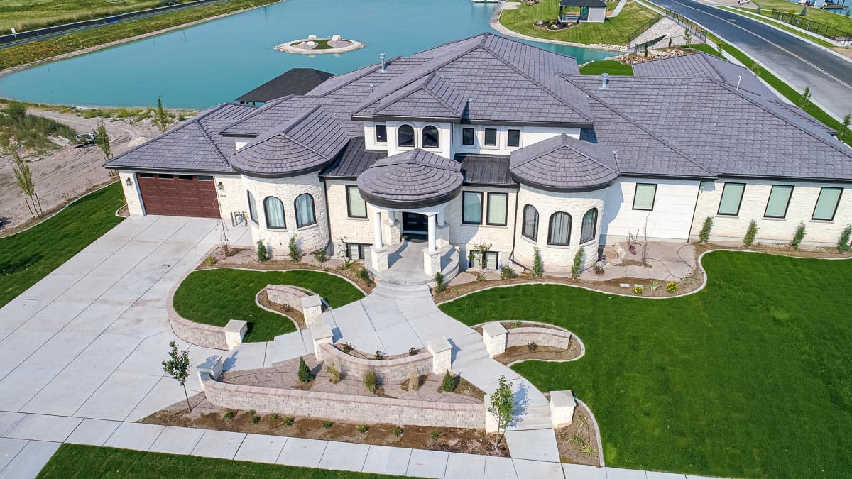 House plan exterior: two-story, multi-gabled roof, arched windows, portico entrance, and attached garage.